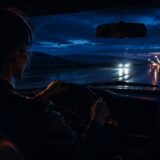 雨上がりの夜の道路を車で走る女性の後ろ姿