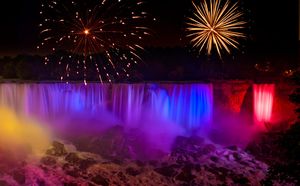 Niagara Falls at night in rainbow colors with fireworks