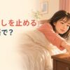 ベッドからスマートフォンの目覚ましを止める女性と「目覚ましを止める」は英語で？の文字