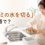 キッチンの流しで生ゴミの余分な水を切る女性と「生ゴミの水を切るは英語で？」の文字