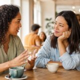 カフェで友人の話に共感しながら耳を傾ける女性