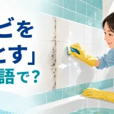 浴室のタイルのカビをスポンジで落とす人と「カビを落とすは英語で？」の文字