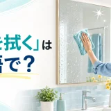 洗面所の鏡を布で拭く人と「鏡を拭くは英語で?」の文字
