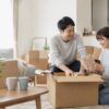 新居で引っ越し荷物を開けながら同棲生活を始める男女