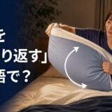 ベッドで枕をひっくり返す人と「枕をひっくり返すは英語で?」の文字