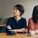 カフェで仲違いして互いに顔を背ける二人の女性