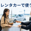 海外の空港レンタカー窓口で英語で予約を確認し、車の鍵を受け取る日本人旅行者