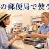 海外の郵便局で日本へ送るはがきと小包について英語で尋ねる日本人旅行者