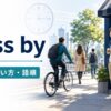 句動詞pass byの意味・使い方・語順を表す、カフェのそばを人や自転車が通り過ぎるイラスト