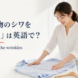 洗濯物のシャツのシワを手で伸ばす女性と英語表現 smooth out the wrinkles