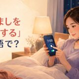 ベッドでスマートフォンの目覚ましを7時にセットする女性と「目覚ましをセットする」は英語で?の文字