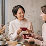 バレンタインカードとチョコレートを手に英語で会話する大人の女性たち